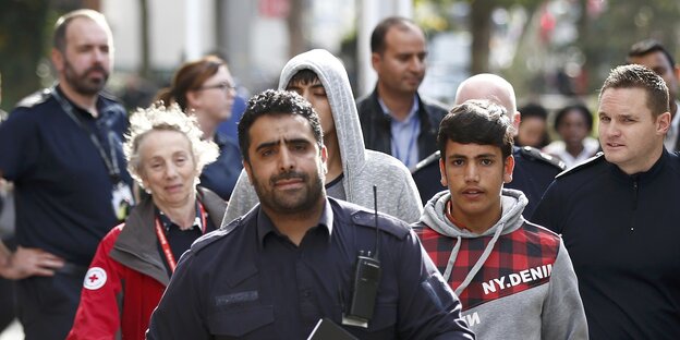 Ein Grenzschutzmitarbeiter, hinter dem eine Gruppe Jugendlicher läuft Ein Grenzschutzmitarbeiter, hinter dem eine Gruppe Jugendlicher läuft