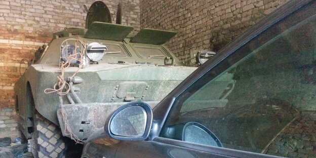 In einer Gragae steht ein Autor vor einem gepanzerten Fahrzeug In einer Gragae steht ein Autor vor einem gepanzerten Fahrzeug