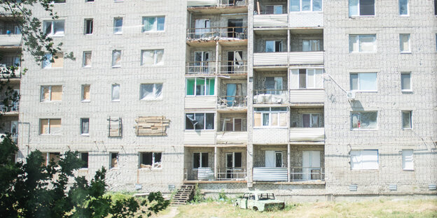Ein Neubaublock mit Einschusslöchern. Manche Fenster sind mit Brettern vernagelt Ein Neubaublock mit Einschusslöchern. Manche Fenster sind mit Brettern vernagelt