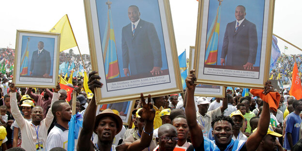 Demonstranten halten eingerahmte Bilder von Joseph Kabila in die Höhe Demonstranten halten eingerahmte Bilder von Joseph Kabila in die Höhe