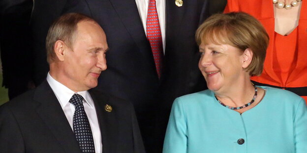 Putin und Merkel schauen sich lächelnd an Putin und Merkel schauen sich lächelnd an
