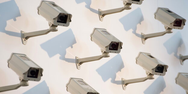 acht Überwachungskameras, die in engem Abstand an einer Wand hängen acht Überwachungskameras, die in engem Abstand an einer Wand hängen