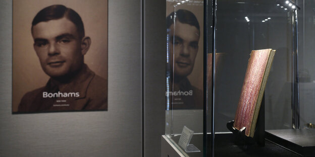 Ein Portrait von Alan Turing hängt im Museum, daneben in einer Vitrine steht sein Notitzbuch Ein Portrait von Alan Turing hängt im Museum, daneben in einer Vitrine steht sein Notitzbuch
