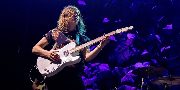 eine Frau mit einer E-Gitarre auf einer Bühne eine Frau mit einer E-Gitarre auf einer Bühne