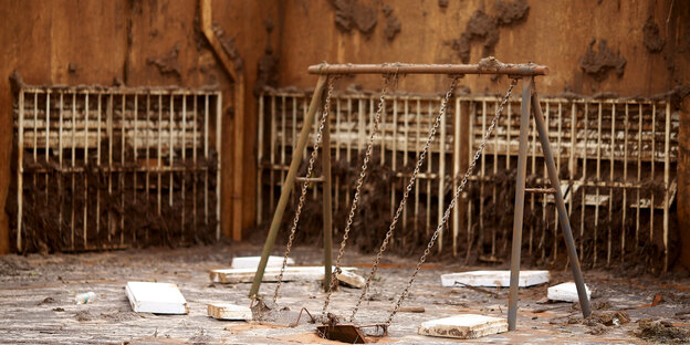 eine Schaukel auf einem schlammverschmierten und verdreckten Schulhof eine Schaukel auf einem schlammverschmierten und verdreckten Schulhof