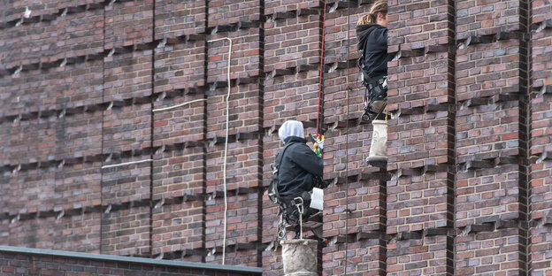 Zwei Fensterputzer hängen an Seilen an einem Hochhaus Zwei Fensterputzer hängen an Seilen an einem Hochhaus