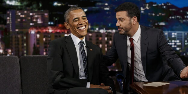 Barack Obama sitzt lachend links vom Moderator, der sich zu ihm beugt und ihm etwas erzählt Barack Obama sitzt lachend links vom Moderator, der sich zu ihm beugt und ihm etwas erzählt