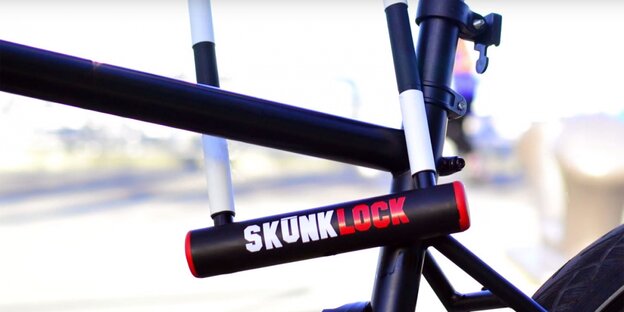 Ein mit einem Bügelschloss (Aufschrift: SkunkLock) abgeschlossener Radrahmen Ein mit einem Bügelschloss (Aufschrift: SkunkLock) abgeschlossener Radrahmen