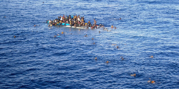 Menschen auf einem gekenterten Boot. Andere schwimmen im Wasser Menschen auf einem gekenterten Boot. Andere schwimmen im Wasser