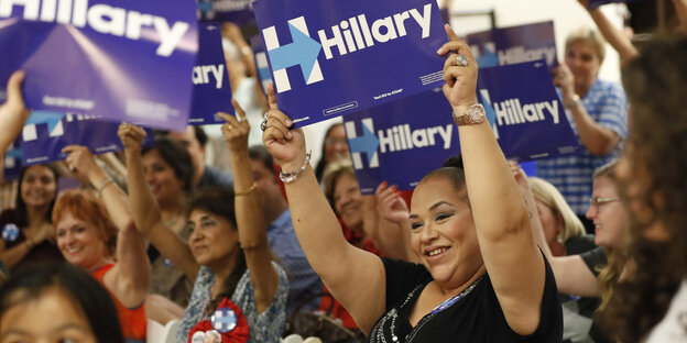 Hispanic-Frauen halten Schilder in die Luft mit „Hillary“ Hispanic-Frauen halten Schilder in die Luft mit „Hillary“