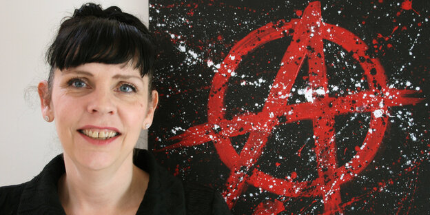 Birgitta Jónsdottír steht neben einem Anarchiezeichen Birgitta Jónsdottír steht neben einem Anarchiezeichen