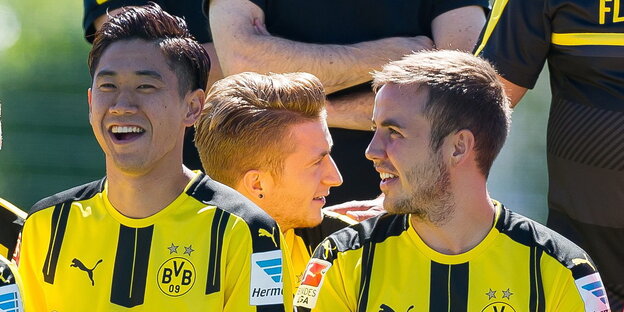 Shingi Kagawa und Mario Götze sitzen nebeneinander in BVB-Trikots und lachen Shingi Kagawa und Mario Götze sitzen nebeneinander in BVB-Trikots und lachen