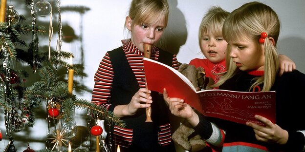Kinder spielen Blockflöte vor dem Weihnachtsbaum Kinder spielen Blockflöte vor dem Weihnachtsbaum