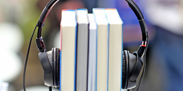Köpfhörer über ein paar Bücher geklemmt, die sie zusammenhalten Köpfhörer über ein paar Bücher geklemmt, die sie zusammenhalten