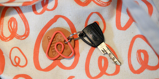 Ein Schlüssel mit einem orangen, dreieckigen Airbnb-Schlüsselanhänger Ein Schlüssel mit einem orangen, dreieckigen Airbnb-Schlüsselanhänger
