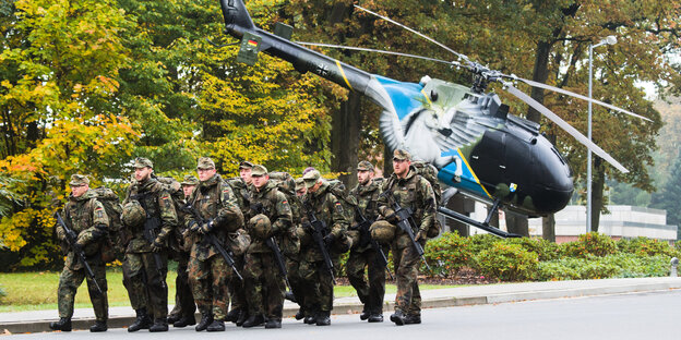 Soldaten marschieren mit Hubschrauber im Hintergrund Soldaten marschieren mit Hubschrauber im Hintergrund