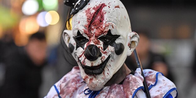Ein als Clown verkleideter Mensch mit blutverschmierter Maske Ein als Clown verkleideter Mensch mit blutverschmierter Maske