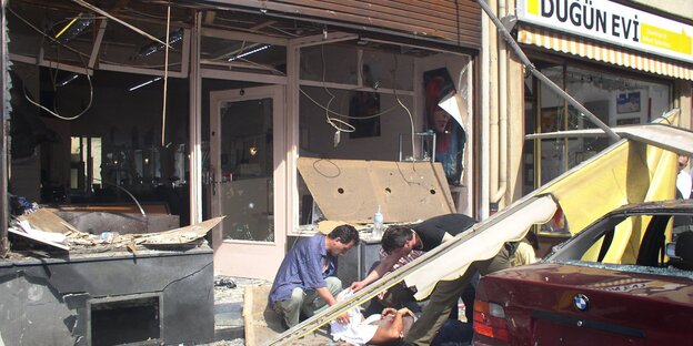Kaputtgesprengtes Ladenlokal in der Kölner Keupstraße 2004 mit Opfern davor Kaputtgesprengtes Ladenlokal in der Kölner Keupstraße 2004 mit Opfern davor