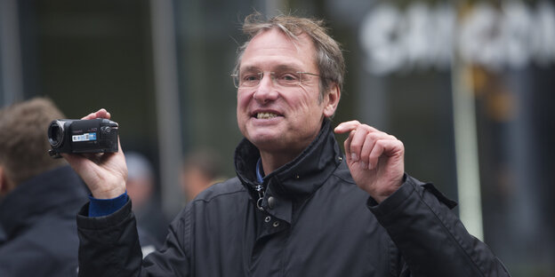 Der Rechtspopulist Michael Johannes Stürzenberger hält eine Kamera hoch und gestikuliert Der Rechtspopulist Michael Johannes Stürzenberger hält eine Kamera hoch und gestikuliert
