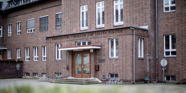 Ein grau-brauner Backsteinbau, an dem „Evangelisches Gymnasium zum grauen Kloster“ steht Ein grau-brauner Backsteinbau, an dem „Evangelisches Gymnasium zum grauen Kloster“ steht