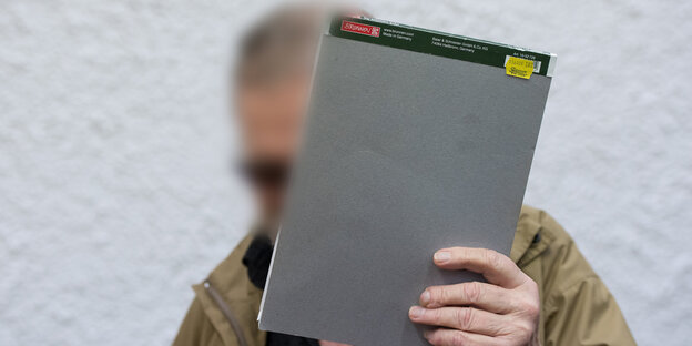 Mann hält sich Schreibblock vors Gesicht, um unerkannt zu bleiben Mann hält sich Schreibblock vors Gesicht, um unerkannt zu bleiben