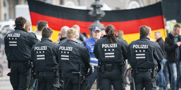 PolizistInnen vor DemonstrantInnen mit einer großen Deutschlandflagge PolizistInnen vor DemonstrantInnen mit einer großen Deutschlandflagge