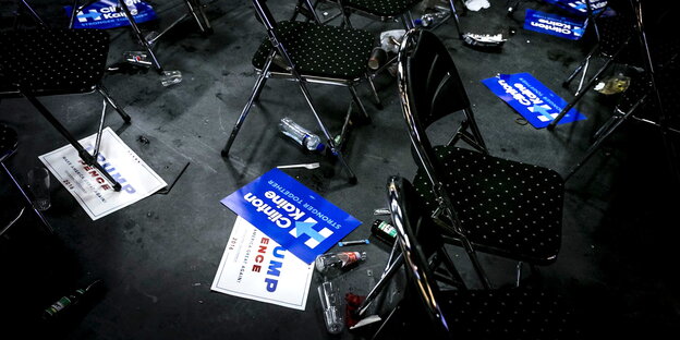 Leere Stühle stehen in einem Raum, auf dem Boden liegen Wahlkampfschilder, die für Donald Trump und Hillary Clinton werben Leere Stühle stehen in einem Raum, auf dem Boden liegen Wahlkampfschilder, die für Donald Trump und Hillary Clinton werben