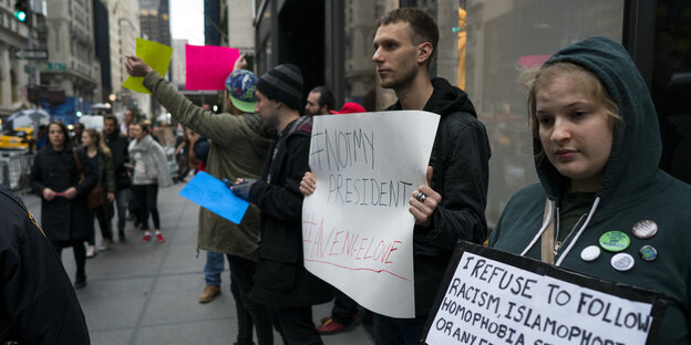 Menschen halten Plakate gegen Trump in die Höhe Menschen halten Plakate gegen Trump in die Höhe