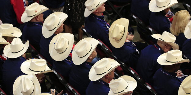 Viele sitzende Männer mit Cowboyhüten Viele sitzende Männer mit Cowboyhüten