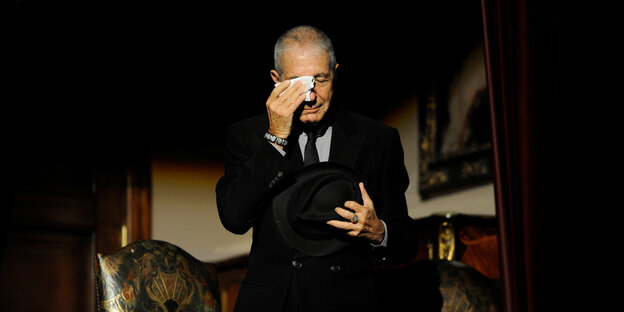 Leonard Cohen im Anzug, den Hut nur in der Hand, tupft sich das Gesicht Leonard Cohen im Anzug, den Hut nur in der Hand, tupft sich das Gesicht
