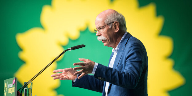ein Mann spricht vor einem großen Grünen-Logo in ein Mikrofon ein Mann spricht vor einem großen Grünen-Logo in ein Mikrofon