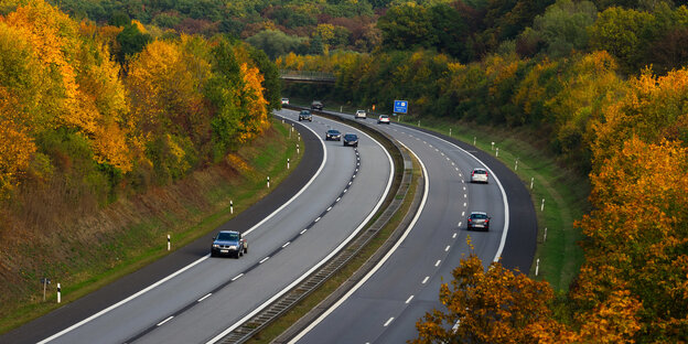 Eine Autobahn in Deutschland inmitten von herbstlich gefärbten Laubbäumen Eine Autobahn in Deutschland inmitten von herbstlich gefärbten Laubbäumen