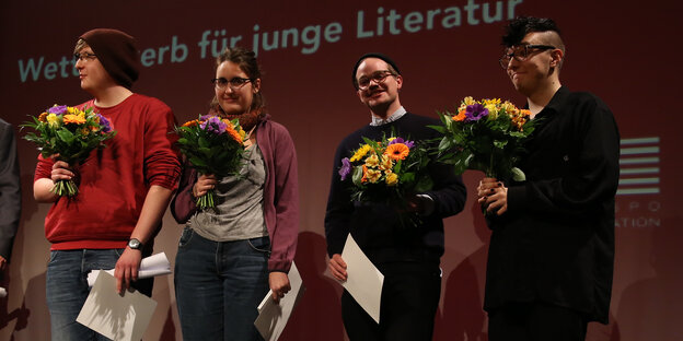 Mit Blumensträußen stehen vier junge Manner und Frauen aunf einem Podium. Mit Blumensträußen stehen vier junge Manner und Frauen aunf einem Podium.