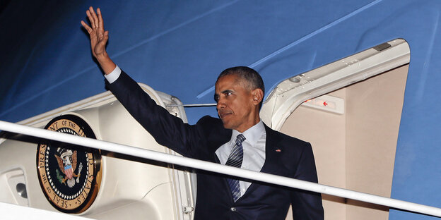 Barack Obama steht im EIngang seines Flugzeugs und hebt die Hand zum Gruß Barack Obama steht im EIngang seines Flugzeugs und hebt die Hand zum Gruß
