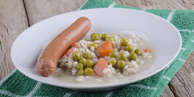 Ein Teller, auf dem Reis, Erbsten, Möhren und Wurst liegen