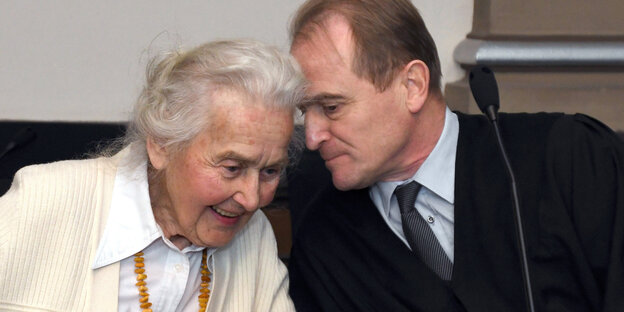 eine Frau im gehobenen Alter tuschelt mit einem Mann eine Frau im gehobenen Alter tuschelt mit einem Mann