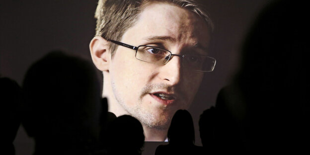 Edward Snowden auf einer Leinwand, im Vordergrund die Silhouetten von Zuschauern Edward Snowden auf einer Leinwand, im Vordergrund die Silhouetten von Zuschauern