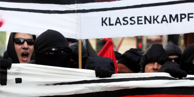 Vermummte mit einem Banner, auf dem Klassenkampf steht Vermummte mit einem Banner, auf dem Klassenkampf steht