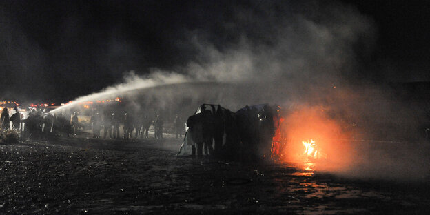 Polizisten versuchen, mit Wasserwerfern ein Feuer der Demonstranten zu löschen Polizisten versuchen, mit Wasserwerfern ein Feuer der Demonstranten zu löschen
