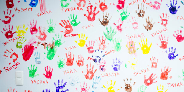 Bunte Abdrücke von Kinderhänden auf einer weißen Wand Bunte Abdrücke von Kinderhänden auf einer weißen Wand