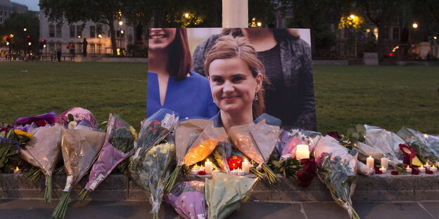 Ein Bild von Jp Cox mit Blumen und Kerzen, die vor dem Bild abgelegt wurden. Ein Bild von Jp Cox mit Blumen und Kerzen, die vor dem Bild abgelegt wurden.