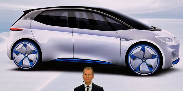 Eine Mann vor einem Bild von einem Elektroauto Eine Mann vor einem Bild von einem Elektroauto