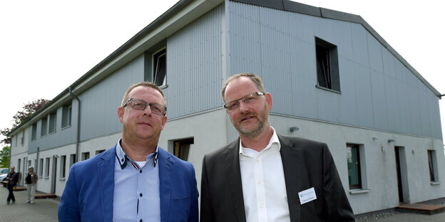 Zwei Männer stehen vor einem Haus aus Beton und Wellblech Zwei Männer stehen vor einem Haus aus Beton und Wellblech