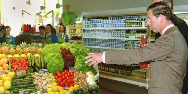 Prince Charles steht in einem Supermarkt vor einem Obstregal Prince Charles steht in einem Supermarkt vor einem Obstregal
