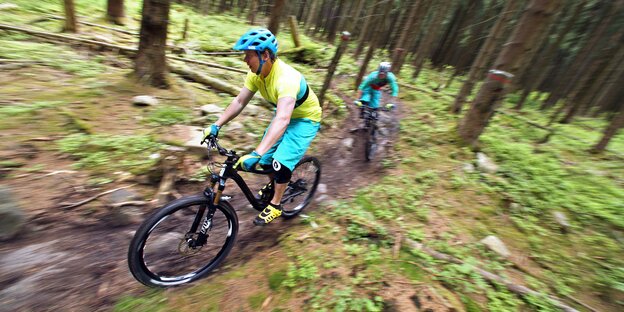 Zwei Mountainbiker fahren durch einen Wald Zwei Mountainbiker fahren durch einen Wald