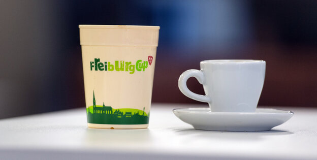 Einwegbecher neben Kaffeetasse Einwegbecher neben Kaffeetasse