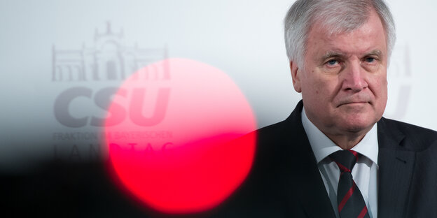 Bayerns Ministerpräsident Horst Seehofer. Im Vordegrund ein roter Punkt, der durch eine Lichtspiegelung entsteht Bayerns Ministerpräsident Horst Seehofer. Im Vordegrund ein roter Punkt, der durch eine Lichtspiegelung entsteht