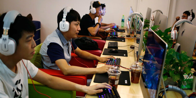Chinesen sitzen nebeneinander in einem Internet-Café vor Computern