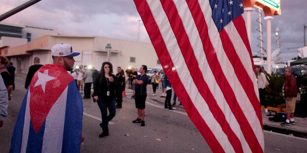 Menschen auf einer Straße, mit kubanischer und US-amerikanischer Flagge Menschen auf einer Straße, mit kubanischer und US-amerikanischer Flagge