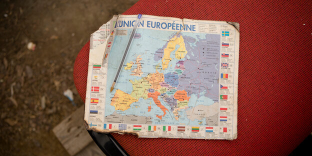Eine zerfledderte Europakarte liegt auf einem roten Polster Eine zerfledderte Europakarte liegt auf einem roten Polster